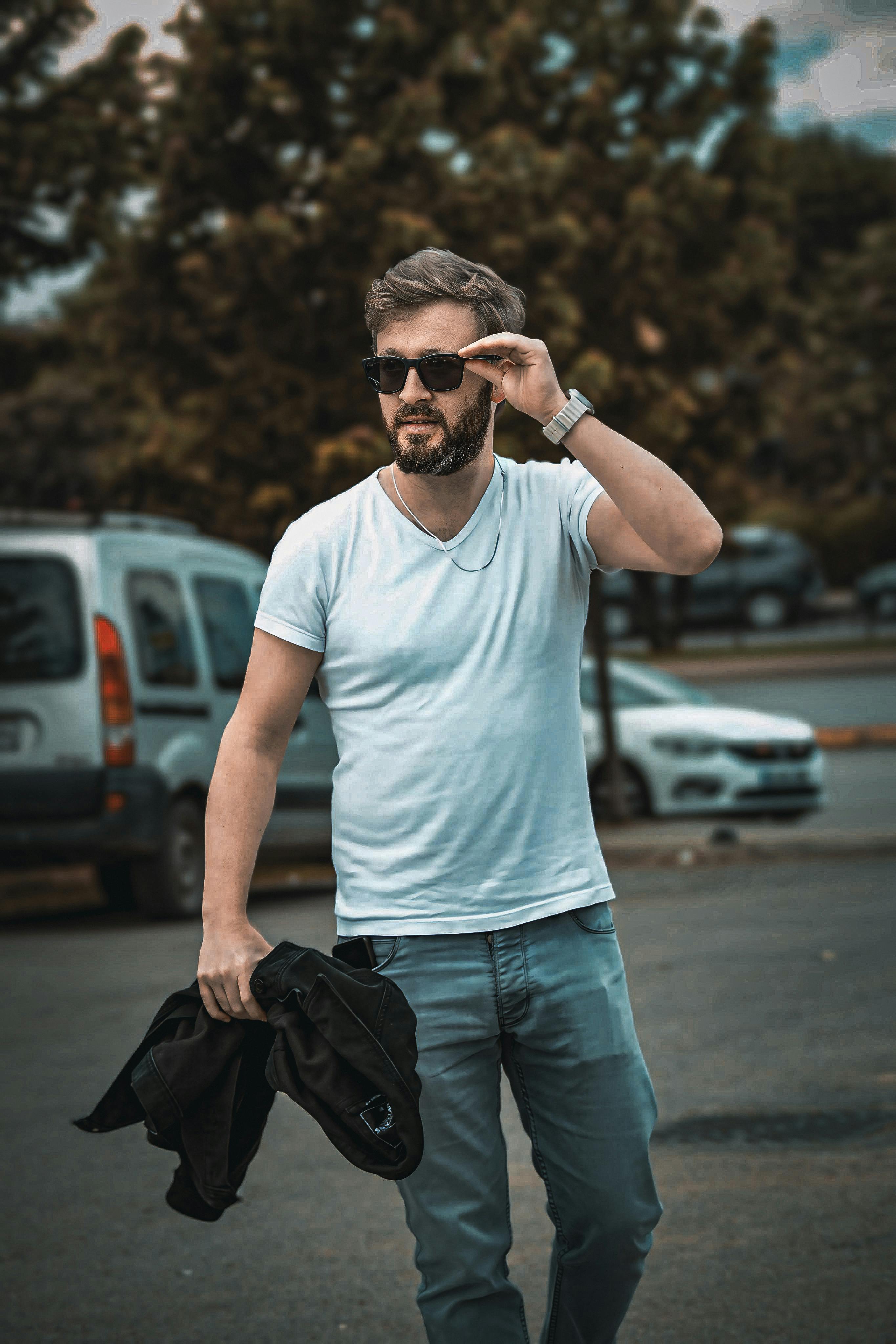 bezplatná Muž V Bundě, Tričku A Džínách Drží Bundu V Ruce Základová fotografie