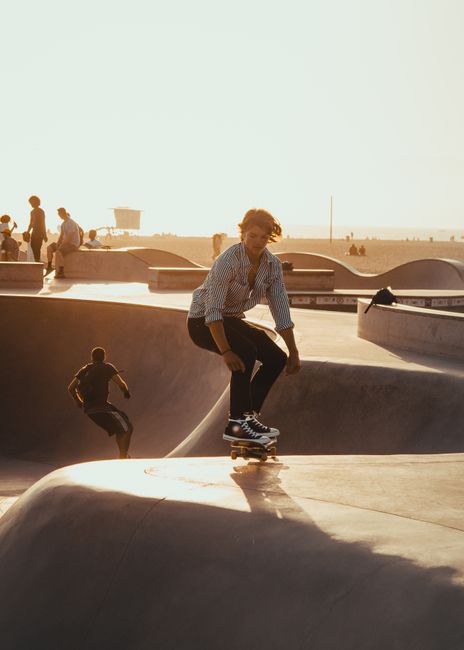 Dynamic shot of skateboarder performing at Venice Beach skatepark at sunset.