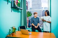 两位同事在现代化的办公室里，对着城市景观进行业务会议