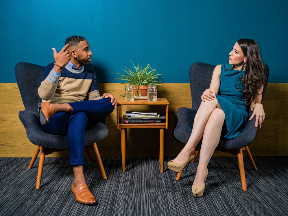 Femme Vêtue D'une Robe Turquoise Assis Sur Une Chaise Parlant à L'homme