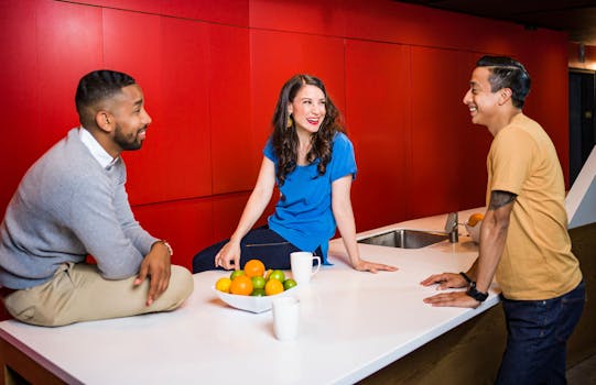 三位成年人在装饰着大胆红色的现代厨房里友好交谈