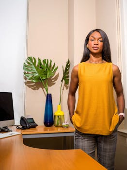 一位时尚女性自信地站在装饰着植物和现代陈设的办公室里