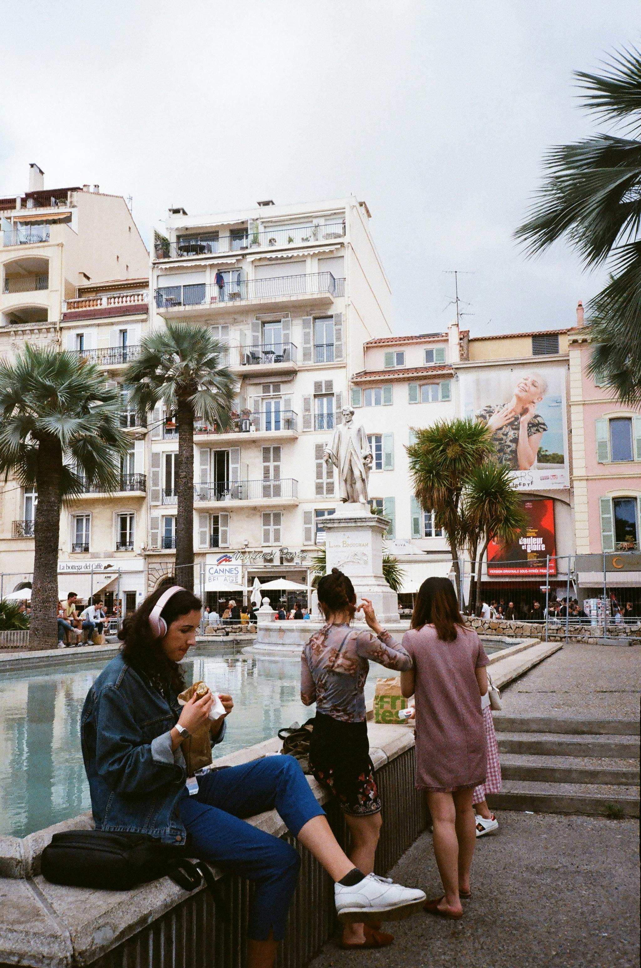 成年人在城市广场的喷泉旁闲逛，周围是建筑和棕榈树