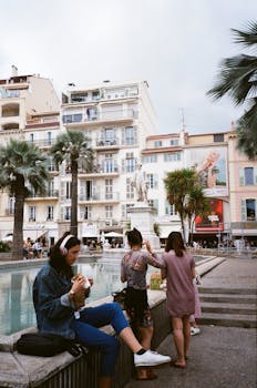 成年人在城市广场的喷泉旁闲逛，周围是建筑和棕榈树