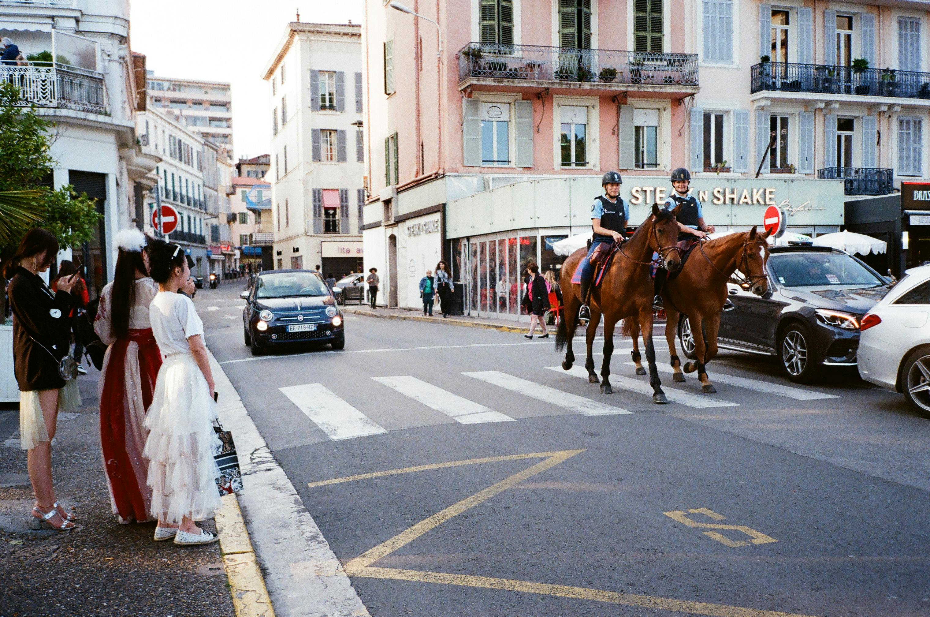 城市街道上，行人、汽车、骑警和历史建筑交织在一起