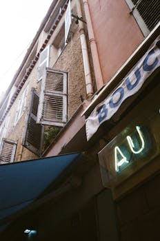 Vintage urban building with shutters and a neon sign, offering a nostalgic city vibe.