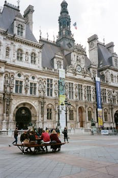 游客在阳光明媚的一天里，欣赏着历史悠久的欧洲建筑错综复杂的外观