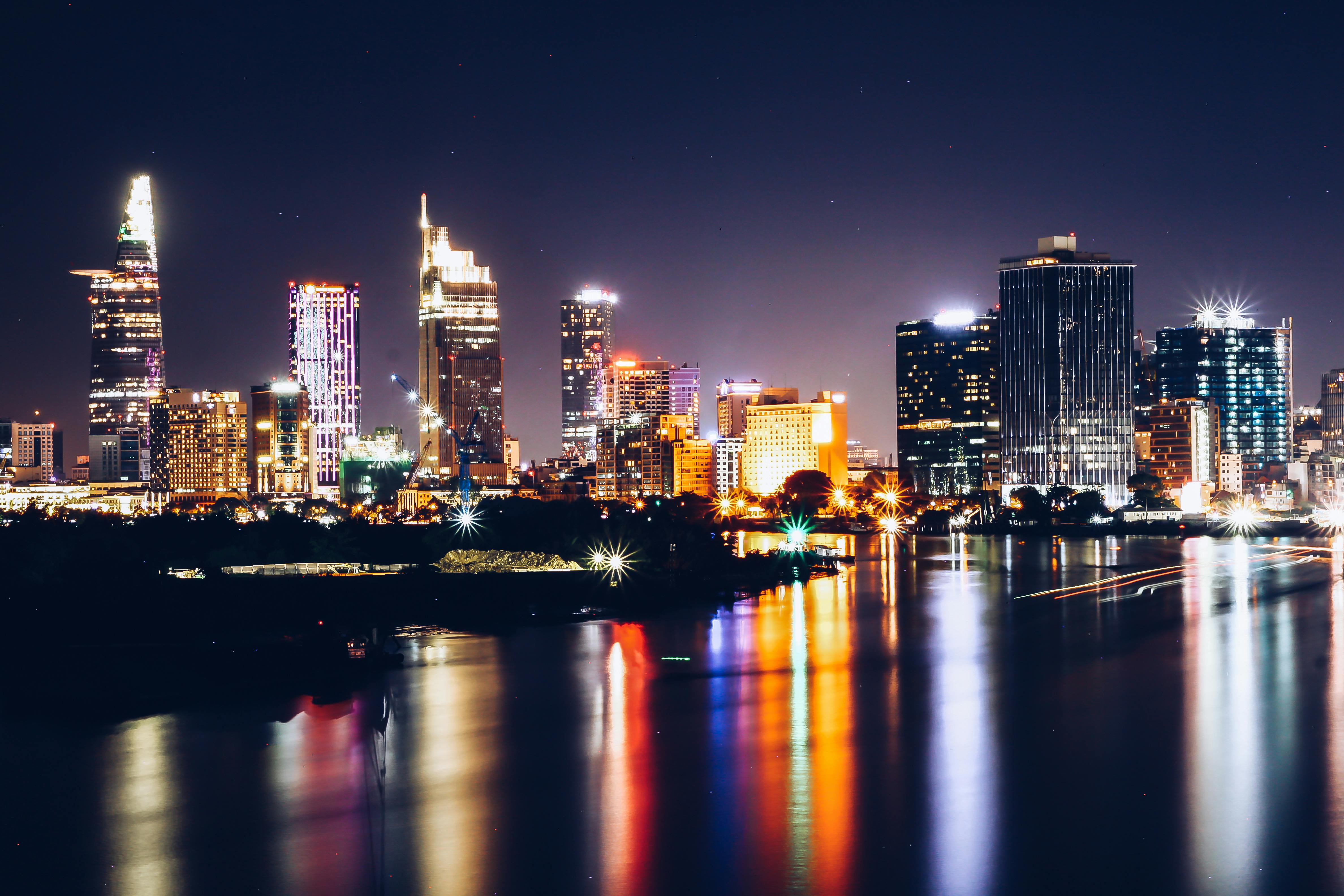 城市天际线的灯光倒映在水面上，展现出充满活力的都市夜景和高层建筑