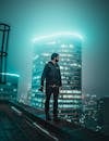 Photo of Man Holding Dslr Camera Walking on Edge of Building Overlooking at Night
