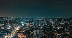 一幅令人惊叹的城市夜景鸟瞰图，展现了夜间灯火通明的建筑与充满活力的城市灯光