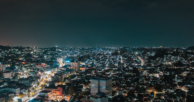 一幅令人惊叹的城市夜景鸟瞰图，展现了夜间灯火通明的建筑与充满活力的城市灯光