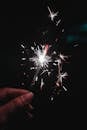 一只手中握着点燃的火花，在黑暗中发出明亮的光芒，非常适合节日庆祝活动