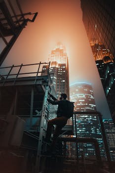 A climber ascends a structure in Minneapolis, with illuminated skyscrapers in the background.