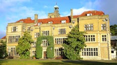 在明亮的天空下，一座令人惊叹的英国豪宅被绿色植物环绕