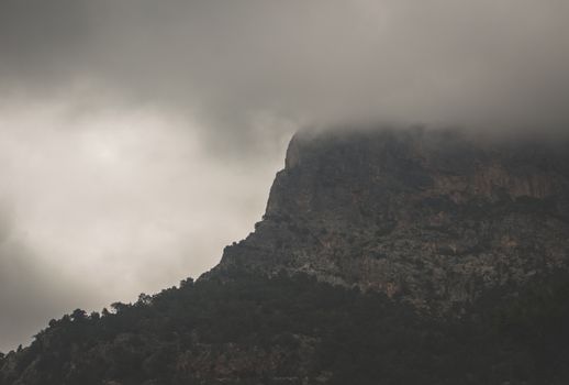 A dramatic view of a fog-covered mountain peak in Muğla, Turkey, capturing nature's mystique.