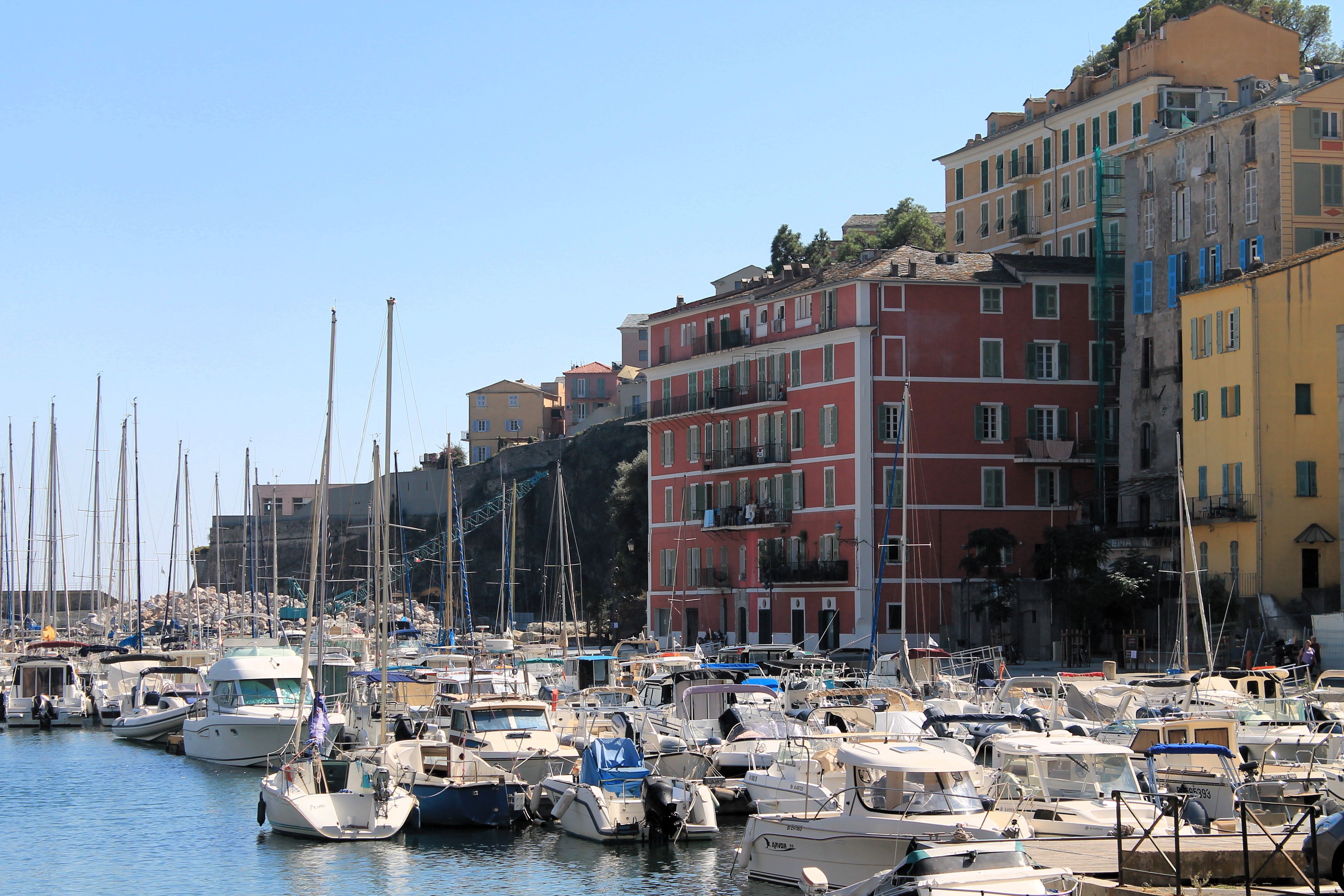 Bastia's vibrant waterfront with moored yachts and colorful buildings under a sunny sky.