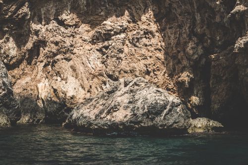 Free Rocky cliff and calm water in Muğla, Turkey, showcasing natural erosion and geological formations. Stock Photo