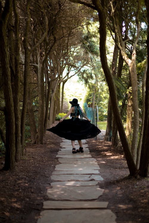 Fotografía De Enfoque Selectivo De Una Mujer Caminando Por Un Sendero Entre árboles