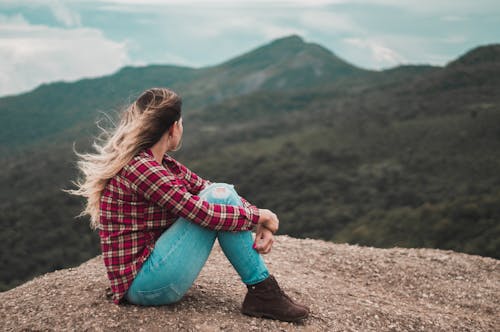 Free Side View Photo of Woman Sitting on Ground Overlooking a Hill Stock Photo