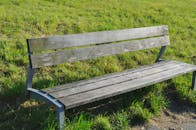 安静的公园里，一张空木凳被绿草环绕，非常适合放松身心