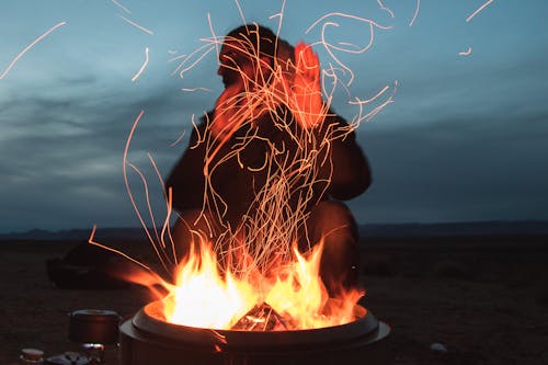 무료 밤 동안 냄비에 직면 화재에 앉아 남자 스톡 사진