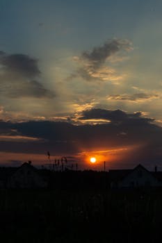 地平线上，美丽的日落映衬着房子的剪影，云彩充满活力
