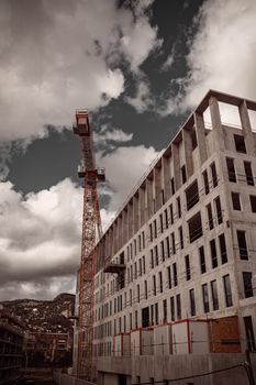 Dramatic view of a construction site with a crane in Toulon under cloudy skies.