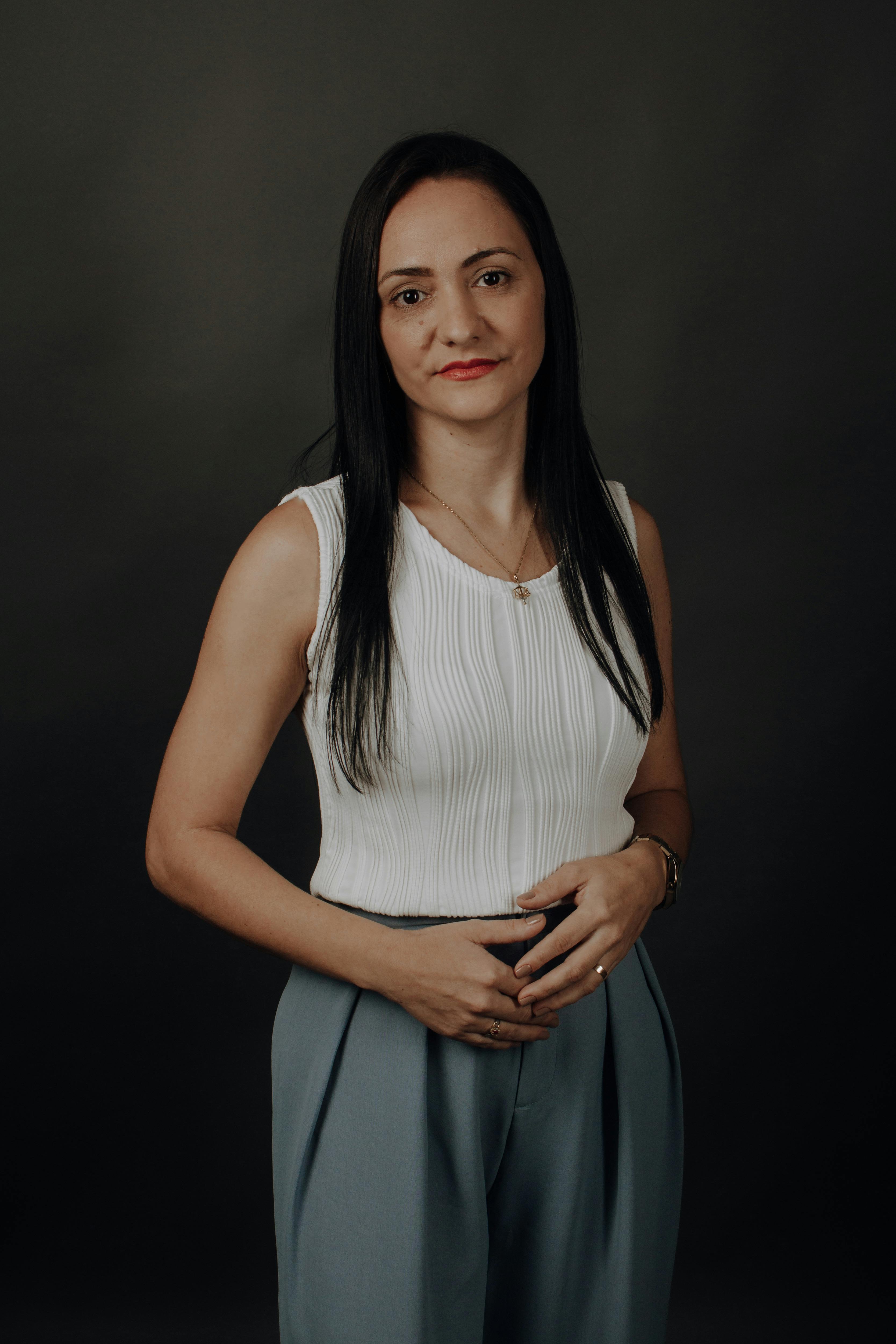 Elegant portrait of a woman with black hair, wearing a white top in a studio setting.