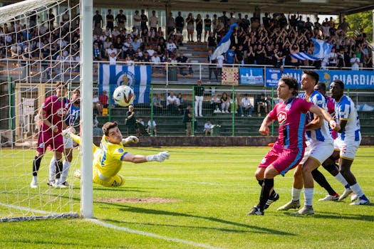 Intense soccer game moment as goalkeeper attempts a save in a crowded stadium.