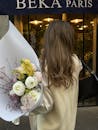 A woman holding a bouquet of flowers in front of a beka paris store