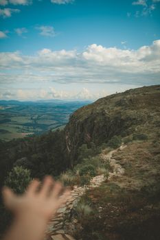 A scenic view of a mountain landscape with a hand reaching out, under a vibrant sky.