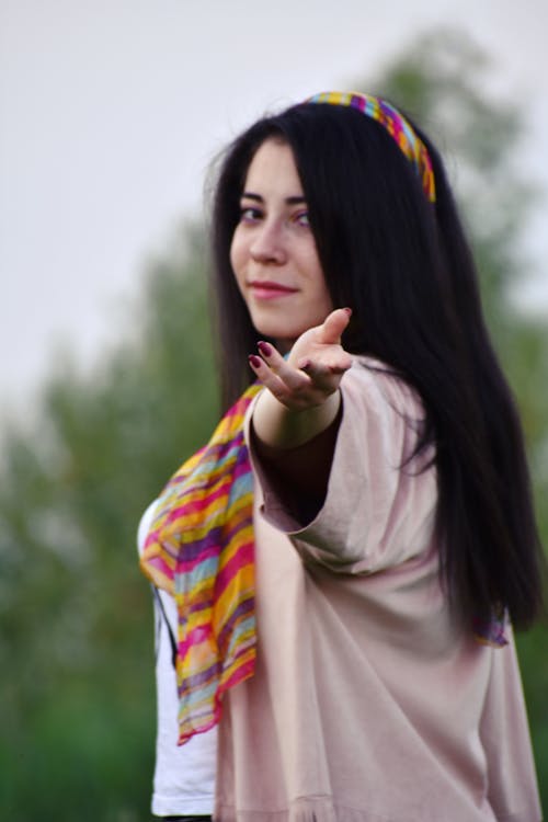 Woman in White Shirt and Pink Blazer Looking over Left Shoulder With Left Hand Outstretched