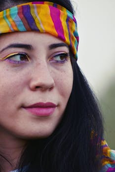Portrait of a young woman with colorful makeup and headband, showcasing vibrant beauty and style.