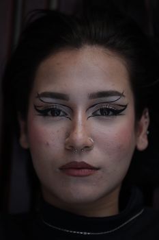 Captivating close-up of a woman with expressive eyeliner and intricate facial makeup.