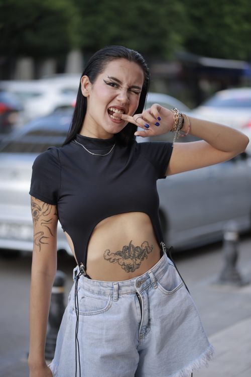 Free Stylish woman with tattoos poses playfully in urban setting, showcasing edgy fashion. Stock Photo
