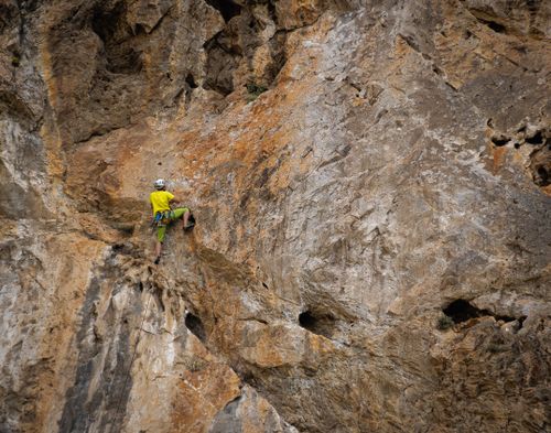 Free Man climbing a rugged rock face in Granada, Andalucía, showcasing adventure and skill. Stock Photo