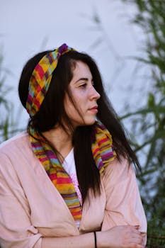 一个年轻女子戴着五颜六色的头巾，在户外的自然环境中，构成了一幅宁静的肖像