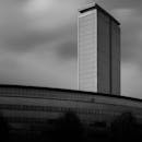 Black and White Photo of a Modern Skyscraper under a Cloudy Sky in City