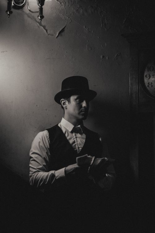 Free Stylish black and white portrait of a man wearing a hat and vest in a dimly lit room. Stock Photo