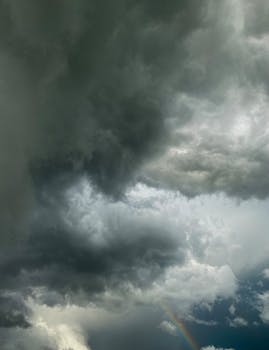 A dramatic cloudscape with looming rain clouds and a hint of a rainbow.