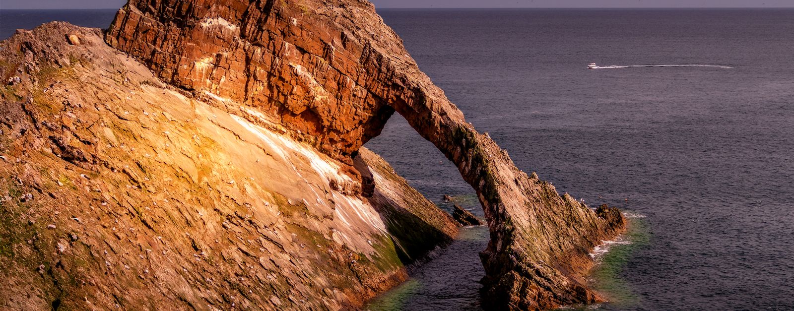Scenic view of Bow Fiddle Rock, a striking sea arch formation in Portknockie, Scotland.