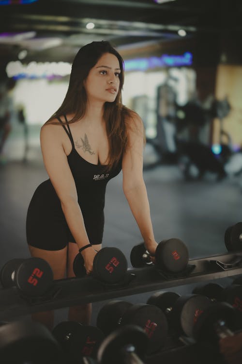 A woman in a black dress is lifting weights