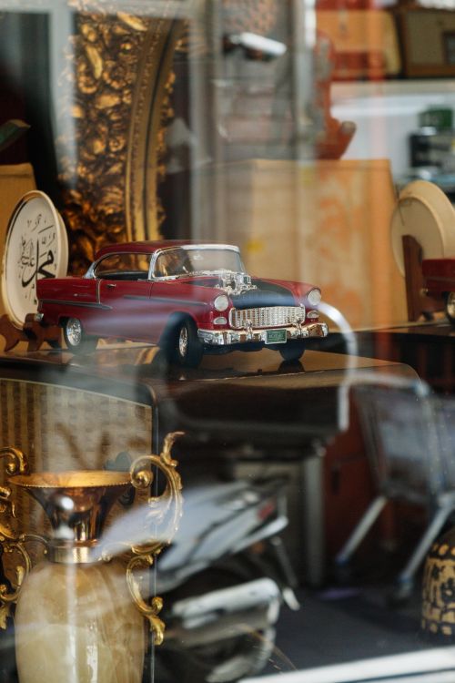 Free A miniature vintage car showcased in an antique store window display. Stock Photo