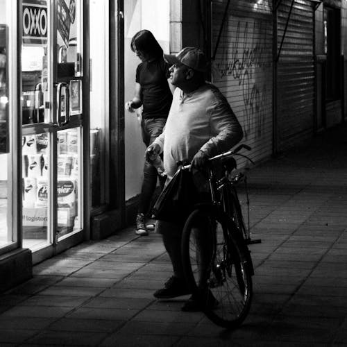 A man and woman walking down the street with a bicycle