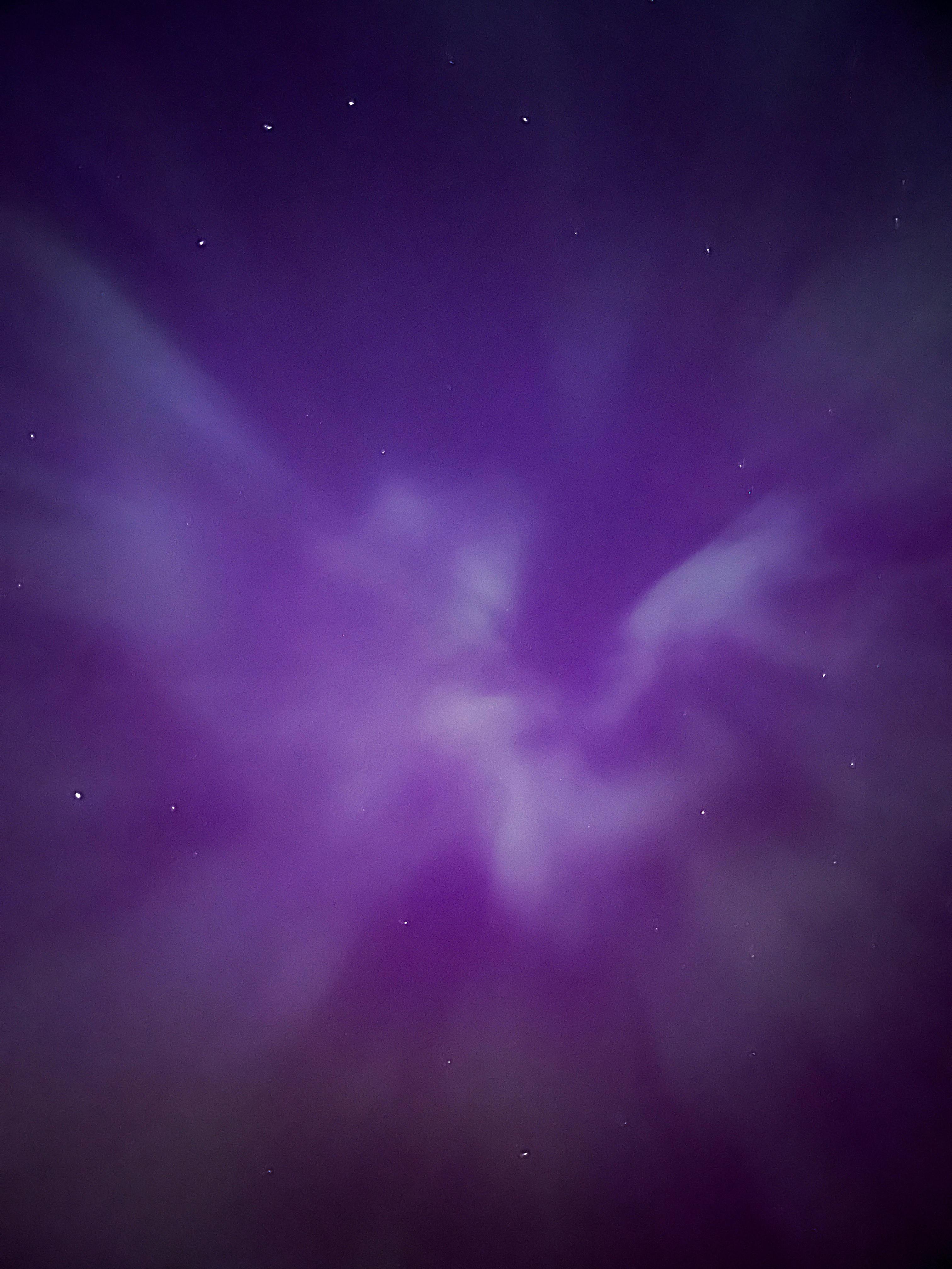 Ethereal purple sky at night with scattered stars and soft, wispy clouds.