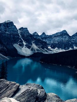 Breathtaking view of Moraine Lake surrounded by majestic Rocky Mountains under a cloudy sky.