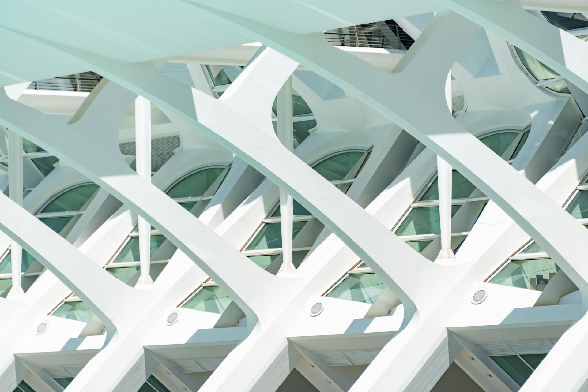 Close-up of white futuristic architectural design with geometric patterns and glass windows.