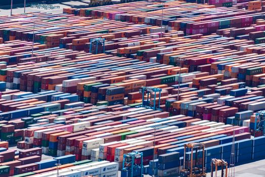 Colorful shipping containers stacked at a busy port, aerial view.