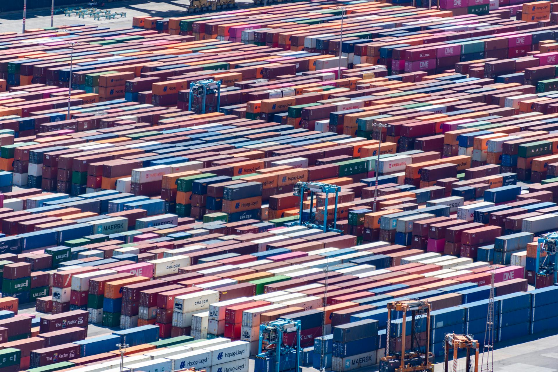 Colorful shipping containers stacked at a busy port, aerial view.