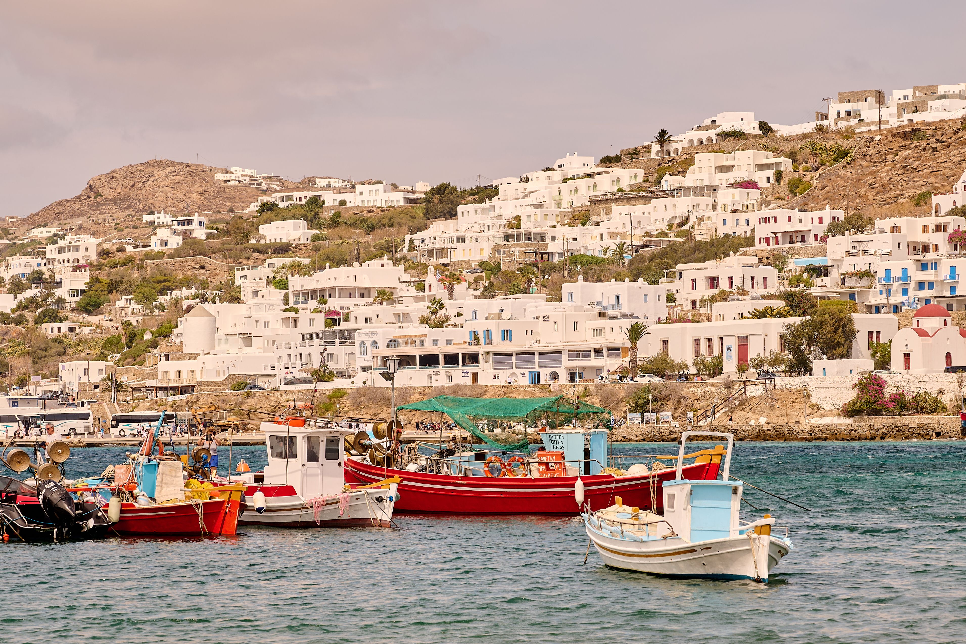 Free Charming white buildings and vibrant boats in Mykonos harbor on a sunny summer day. Stock Photo